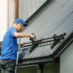 Roofer installing snow guard on metal roof